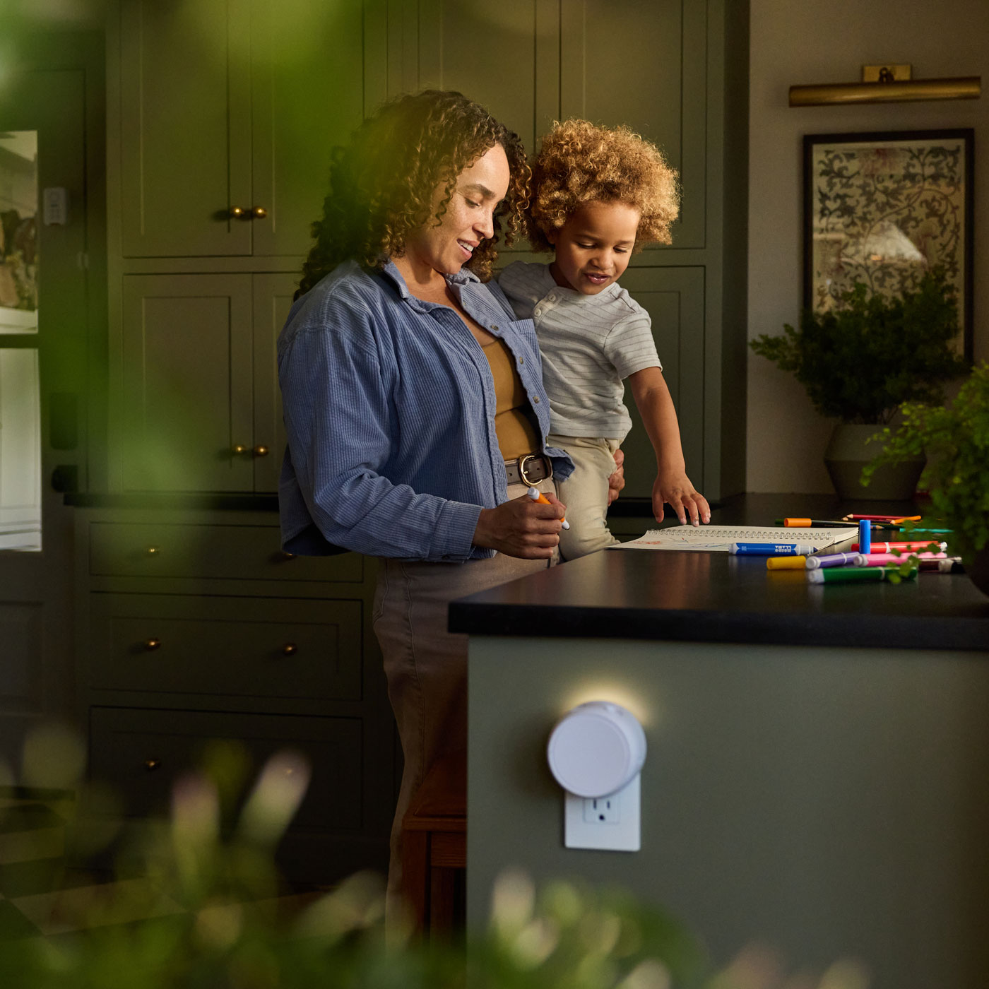 Mom and child drawing together in a kitchen with Pura smart diffuser plugged in
