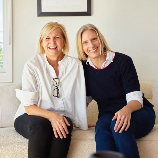 Mersea founders Lina and Mel laughing together on a couch.