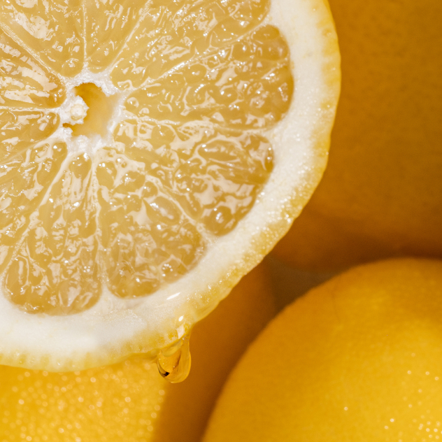 Close-up of a juicy lemon half next to whole lemons.