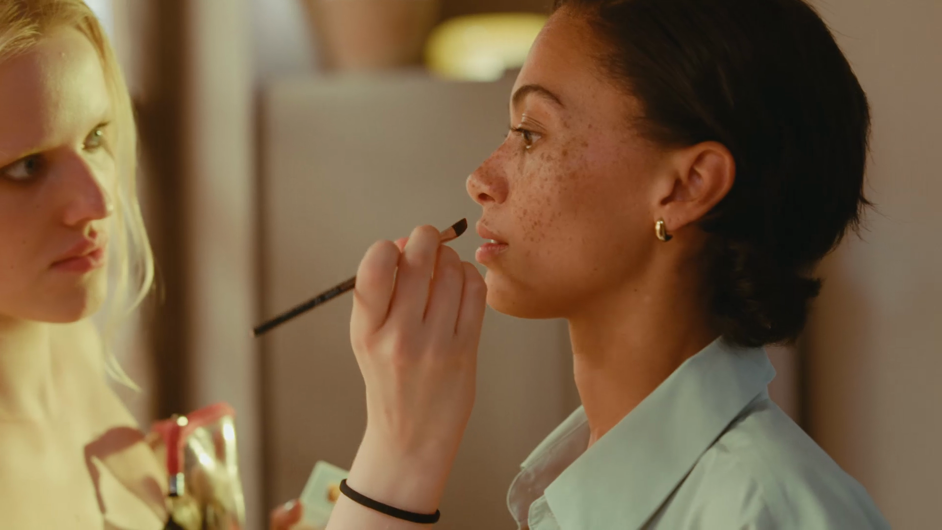 Behind-the-scenes photo of a makeup artist applying finishing touches to a model during Pura's fragrance campaign film shoot