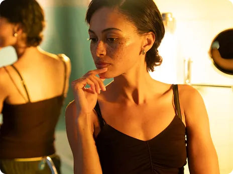 Close-up behind-the-scenes photo of a model in warm golden lighting during Pura's fragrance campaign shoot.