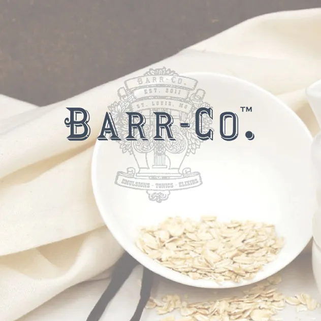 Bowl of oats on folded linen, overlaid with the Barr-Co. wordmark and a vintage 'Est. 2011, St. Louis, MO' emblem.