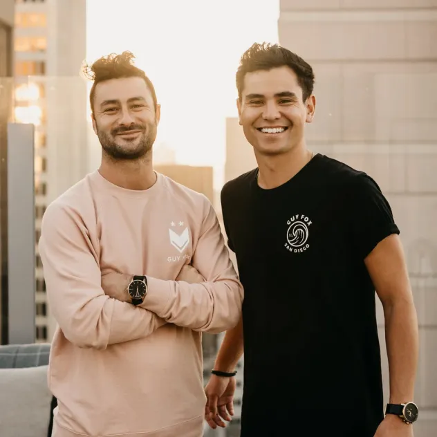 Guy Fox co-founders smiling together on a rooftop, wearing Guy Fox branded shirts