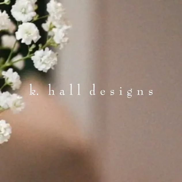 Blurred baby's breath flowers with the 'k. hall designs' logo overlaid on a soft pink background
