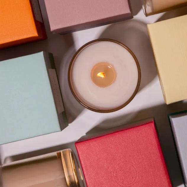 Overhead view of a lit candle surrounded by colorful gift boxes.
