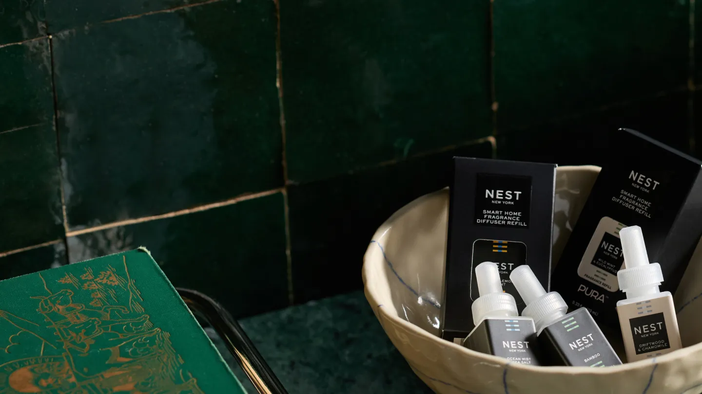 NEST New York fragrance refills for Pura in a ceramic bowl against dark green tile